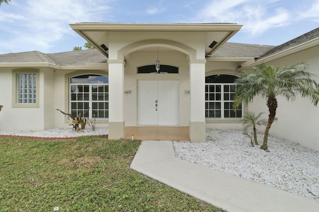 view of exterior entry featuring a lawn