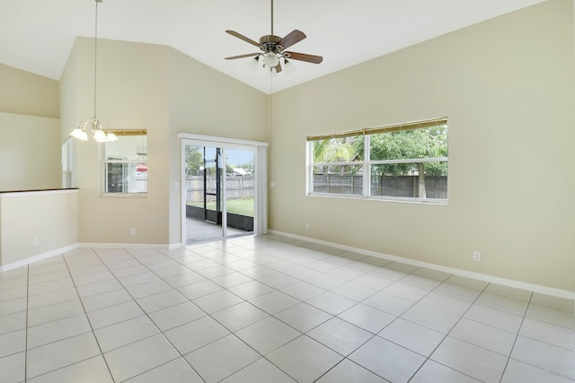 empty room with high vaulted ceiling, light tile patterned flooring, and ceiling fan with notable chandelier