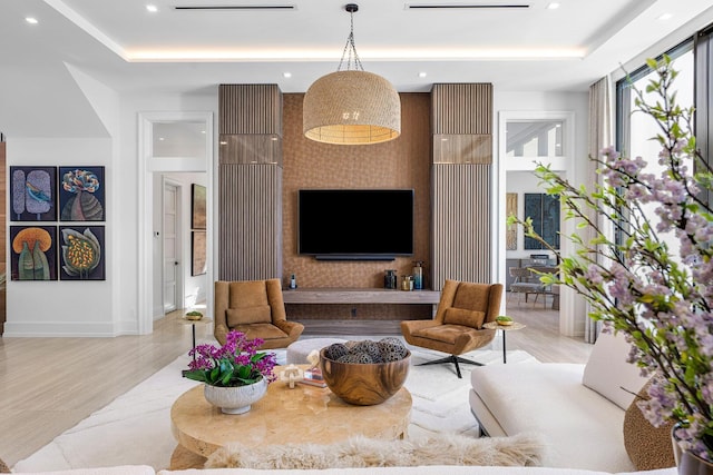 living room with a raised ceiling and light wood-type flooring