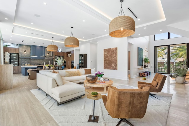 living room featuring a towering ceiling, a tray ceiling, and light hardwood / wood-style flooring