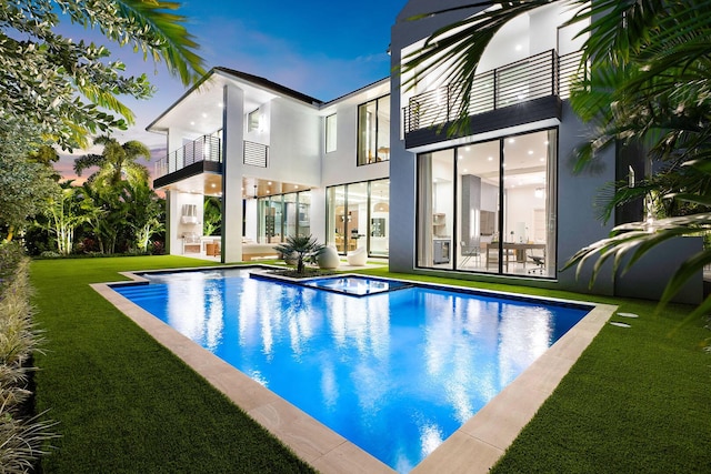 back of house featuring a lawn and a balcony