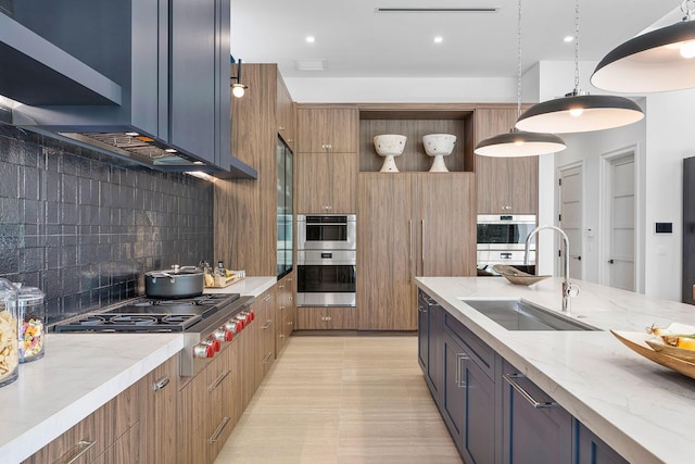 kitchen with light stone countertops, sink, hanging light fixtures, stainless steel appliances, and tasteful backsplash