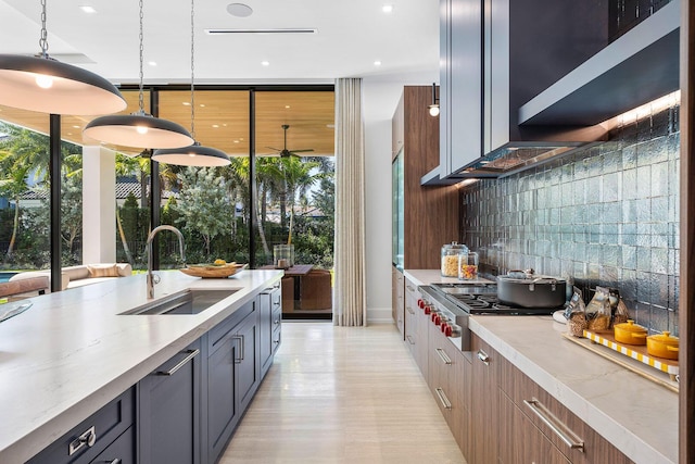 kitchen with backsplash, sink, hanging light fixtures, gray cabinets, and stainless steel gas cooktop