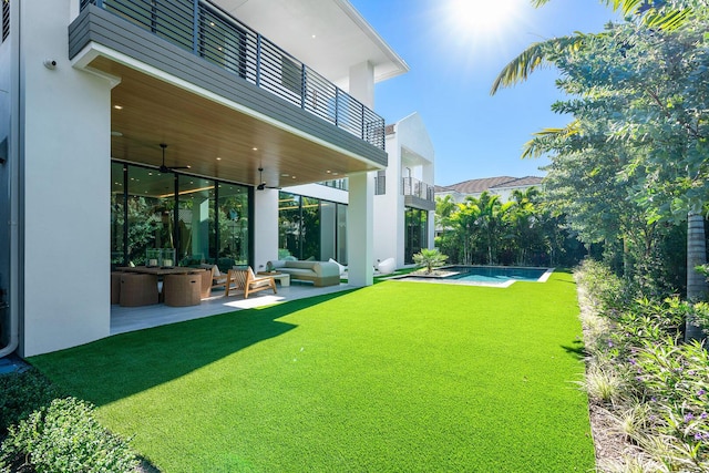 view of yard featuring outdoor lounge area, ceiling fan, a balcony, and a patio