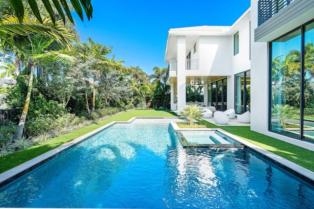 view of swimming pool featuring a lawn and an in ground hot tub