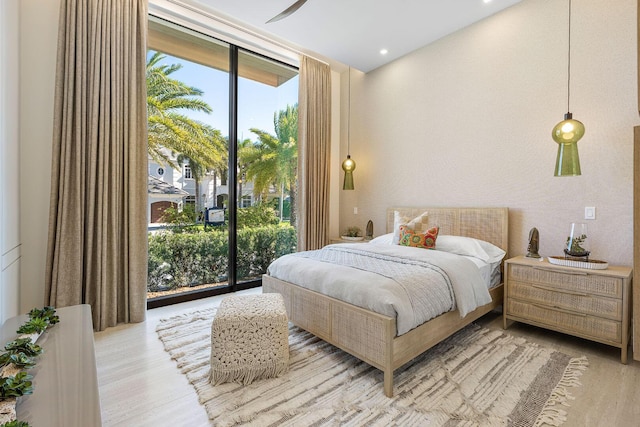 bedroom featuring expansive windows, light wood-type flooring, access to outside, and ceiling fan