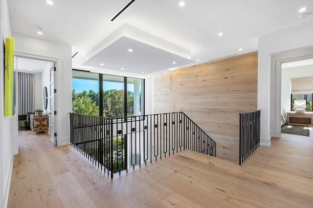 hall featuring a wealth of natural light, wood walls, and light wood-type flooring