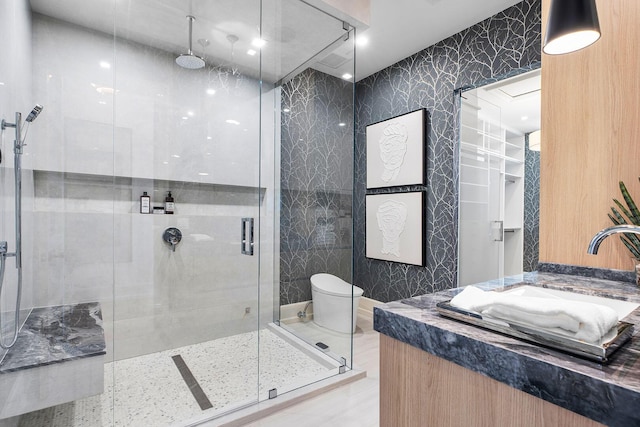 bathroom with vanity, toilet, an enclosed shower, and tile walls