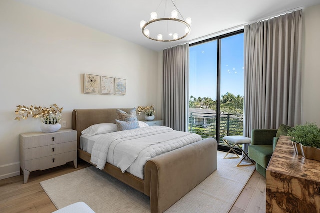 bedroom featuring a wall of windows, a notable chandelier, and light wood-type flooring