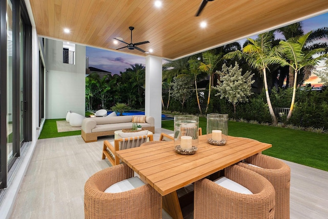 patio terrace at dusk featuring an outdoor living space, ceiling fan, and a lawn