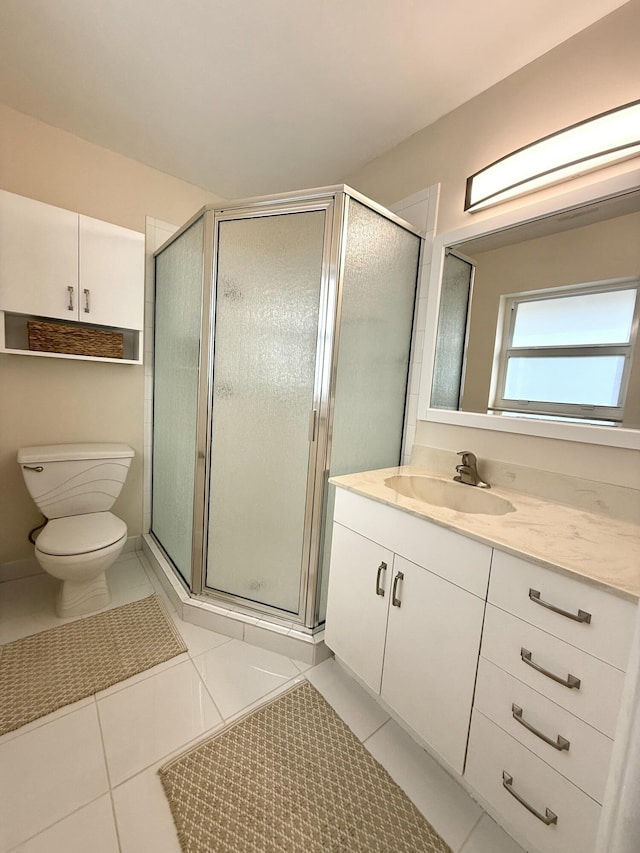 bathroom featuring tile patterned floors, vanity, toilet, and a shower with shower door