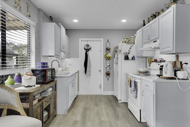 167 SW Tulip Blvd, Port Saint Lucie, FL 34953 - kitchen with white appliances, under cabinet range hood, a sink, light wood-type flooring, and decorative backsplash