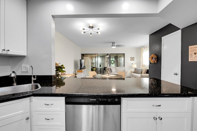 kitchen featuring stainless steel dishwasher, white cabinets, sink, and dark stone counters