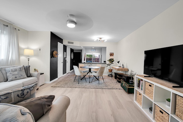 living room with plenty of natural light, ceiling fan, and light hardwood / wood-style flooring