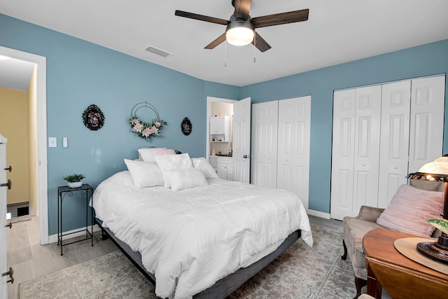 bedroom with ceiling fan, two closets, and light wood-type flooring