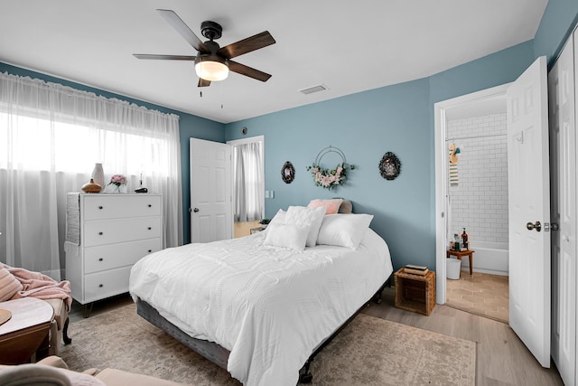 bedroom with ceiling fan, ensuite bathroom, and light hardwood / wood-style floors