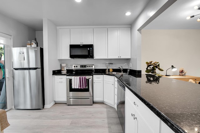 kitchen featuring sink, black appliances, dark stone countertops, white cabinets, and light hardwood / wood-style floors