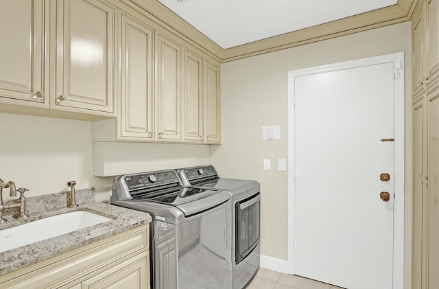 laundry room featuring washing machine and clothes dryer, sink, light tile patterned floors, and cabinets