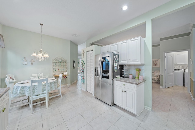 kitchen featuring stainless steel fridge with ice dispenser, light stone counters, backsplash, washer / clothes dryer, and white cabinets