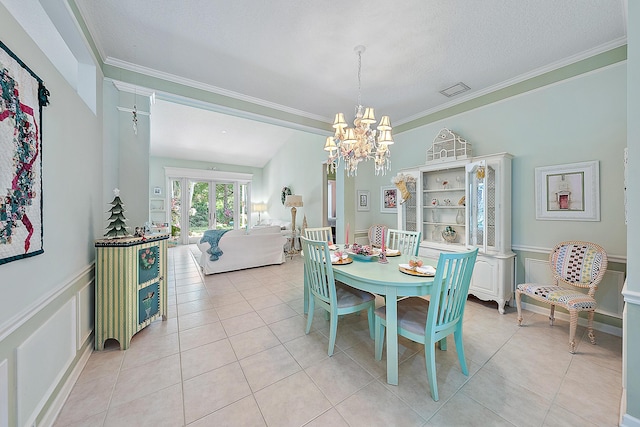 tiled dining room with a chandelier, a textured ceiling, and ornamental molding