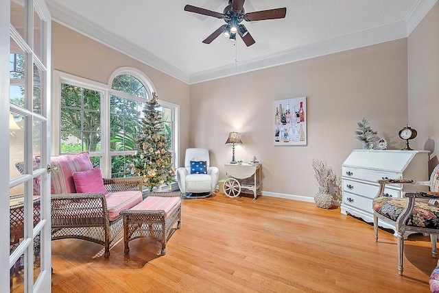 living area with light hardwood / wood-style flooring, ceiling fan, and crown molding