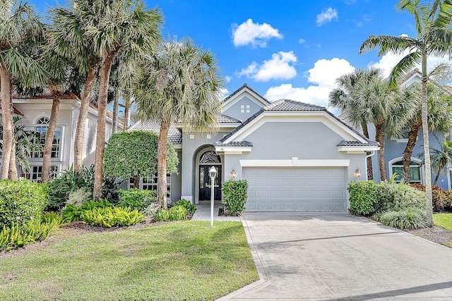 26 Princewood Ln, Palm Beach Gardens, FL 33410 - mediterranean / spanish house featuring a garage, stucco siding, driveway, a tile roof, and a front yard