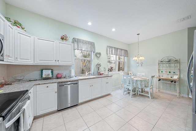 kitchen featuring tasteful backsplash, white cabinetry, stainless steel appliances, and a notable chandelier