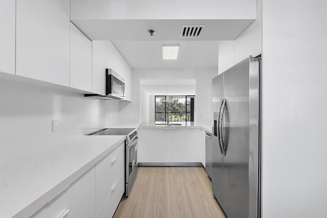 kitchen with white cabinets, appliances with stainless steel finishes, and light wood-type flooring