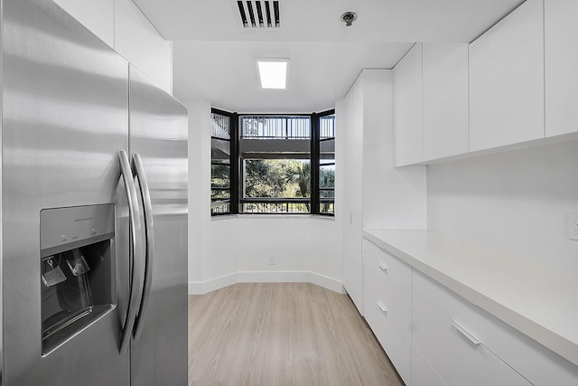 kitchen with white cabinets, stainless steel fridge with ice dispenser, and light hardwood / wood-style flooring