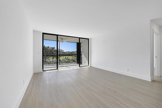 unfurnished room featuring a wall of windows, ceiling fan, and light wood-type flooring