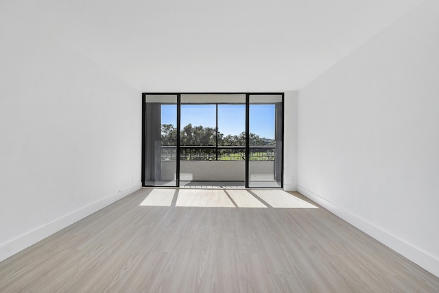 unfurnished room with light wood-type flooring and a wall of windows