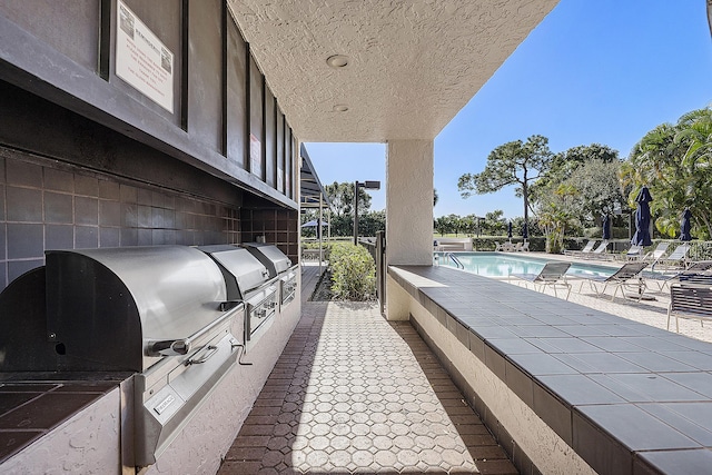 view of patio with area for grilling and a community pool