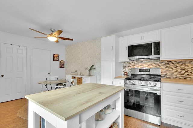 kitchen with white cabinets, light hardwood / wood-style floors, stainless steel appliances, and tasteful backsplash