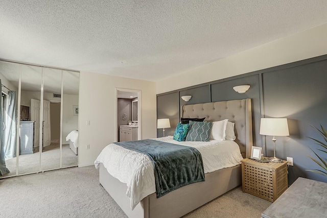 carpeted bedroom featuring ensuite bath and a textured ceiling