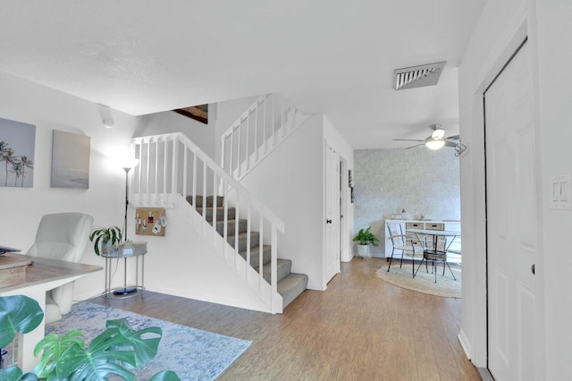 stairs featuring ceiling fan and hardwood / wood-style floors