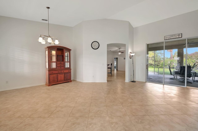 tiled empty room with high vaulted ceiling and ceiling fan with notable chandelier