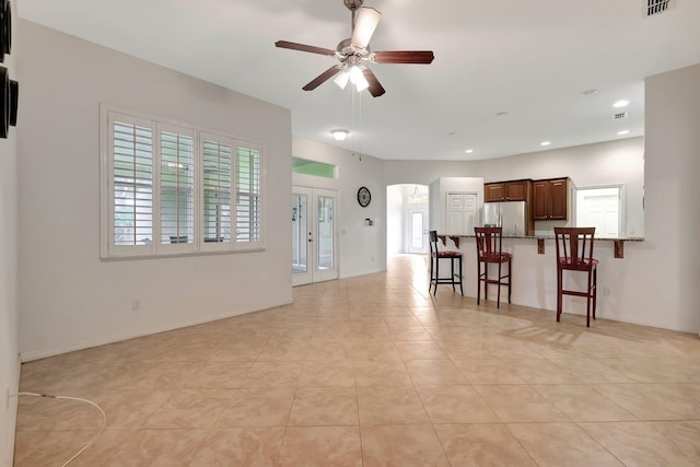 living room with a wealth of natural light, french doors, ceiling fan, and light tile patterned floors