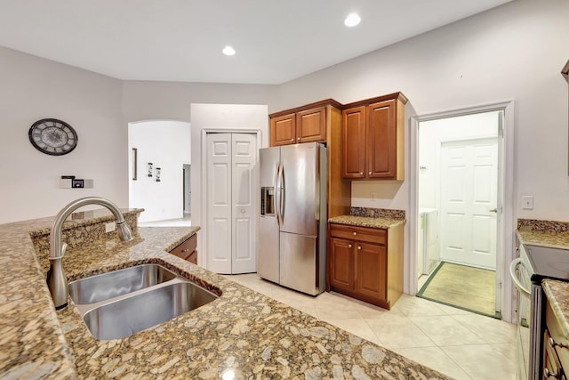 kitchen with light stone counters, sink, light tile patterned flooring, and stainless steel appliances