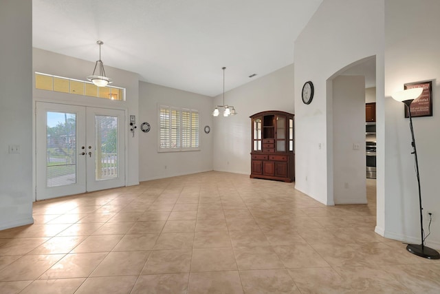 tiled entrance foyer featuring french doors, lofted ceiling, a wealth of natural light, and a notable chandelier