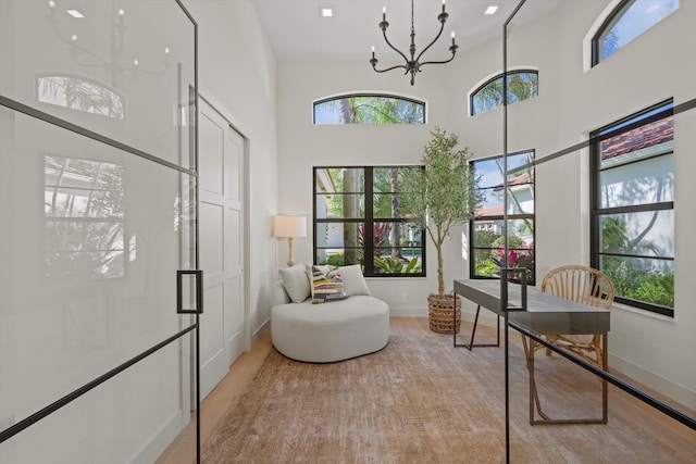 office space with a chandelier, light hardwood / wood-style floors, and a high ceiling