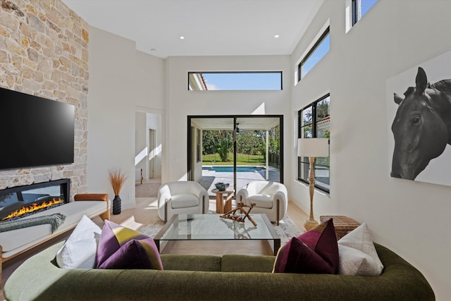 living room with a stone fireplace, light hardwood / wood-style floors, and a high ceiling