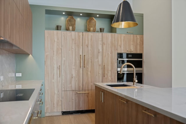 kitchen featuring light stone countertops, sink, double oven, light hardwood / wood-style floors, and black electric cooktop