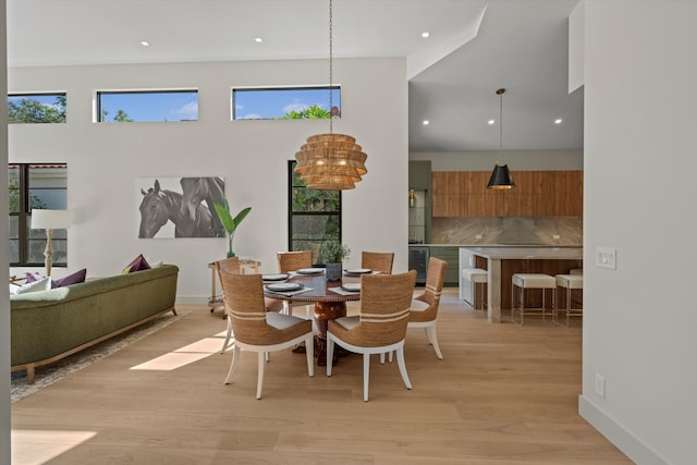 dining area with a chandelier, a high ceiling, and light hardwood / wood-style floors