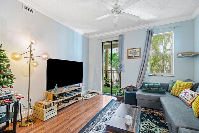 living room with hardwood / wood-style floors, ceiling fan with notable chandelier, a textured ceiling, and ornamental molding