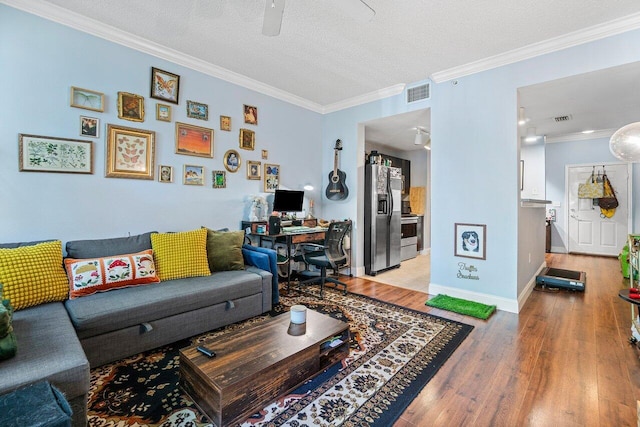 living room featuring ceiling fan, ornamental molding, a textured ceiling, and hardwood / wood-style flooring