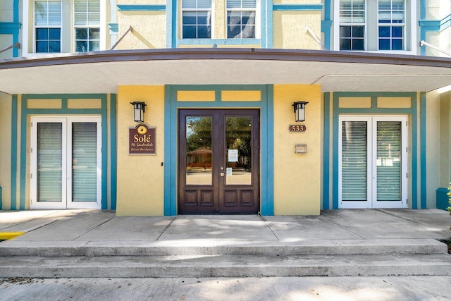 view of exterior entry with covered porch and french doors