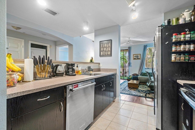 kitchen featuring appliances with stainless steel finishes, light wood-type flooring, a textured ceiling, ceiling fan, and sink