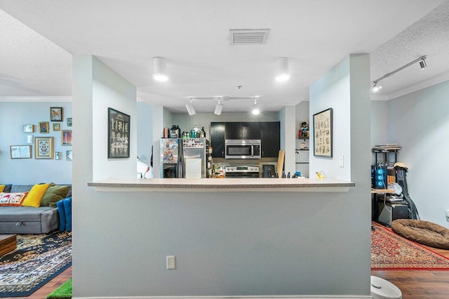 kitchen featuring rail lighting, wood-type flooring, ornamental molding, and appliances with stainless steel finishes