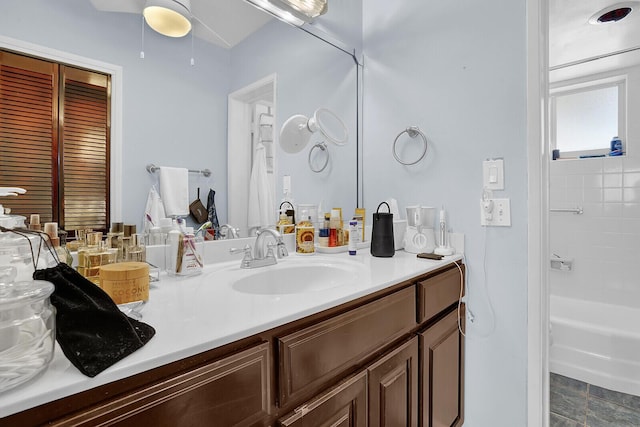 bathroom with vanity, tiled shower / bath combo, and ceiling fan