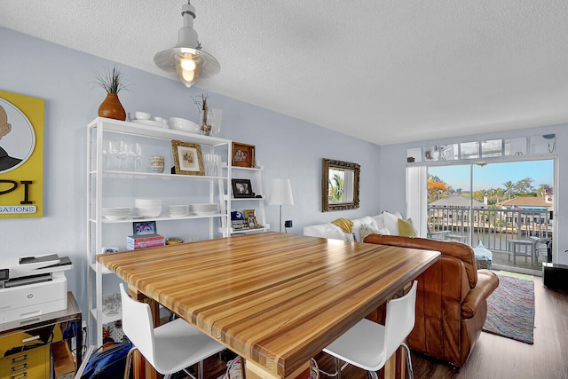 dining space with wood-type flooring, a textured ceiling, and a water view